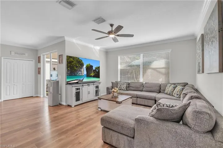 Living room with ceiling fan, ornamental molding, and light hardwood / wood-style flooring