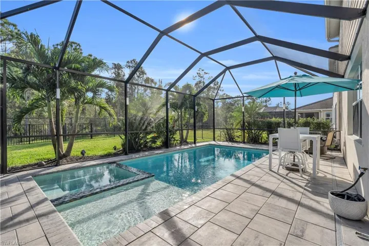 View of swimming pool with an in ground hot tub, a yard, glass enclosure, and a patio area