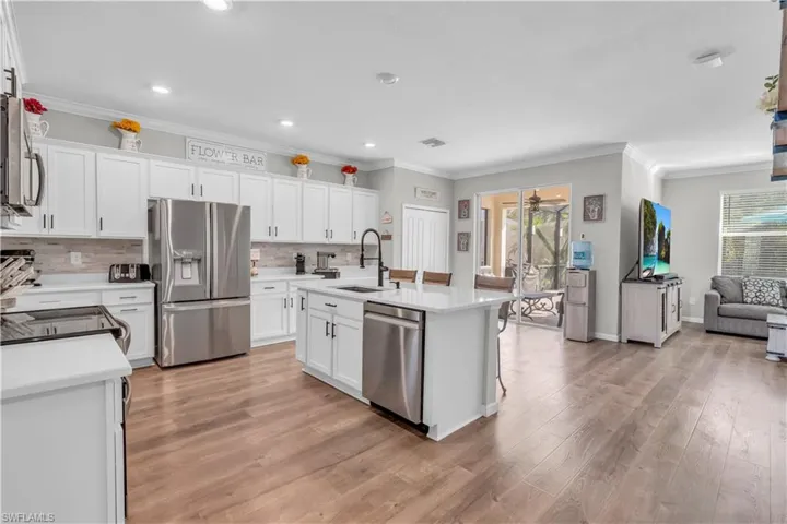 Kitchen featuring a center island with sink, sink, light hardwood / wood-style flooring, appliances with stainless steel finishes, and white cabinetry