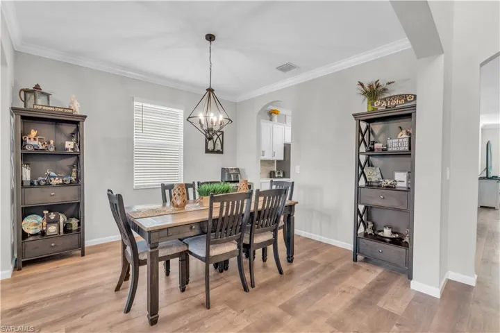 Dining space featuring crown molding, light hardwood / wood-style floors, and a notable chandelier
