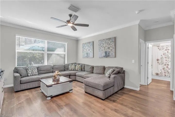 Living room featuring ceiling fan, light wood-type flooring, and crown molding