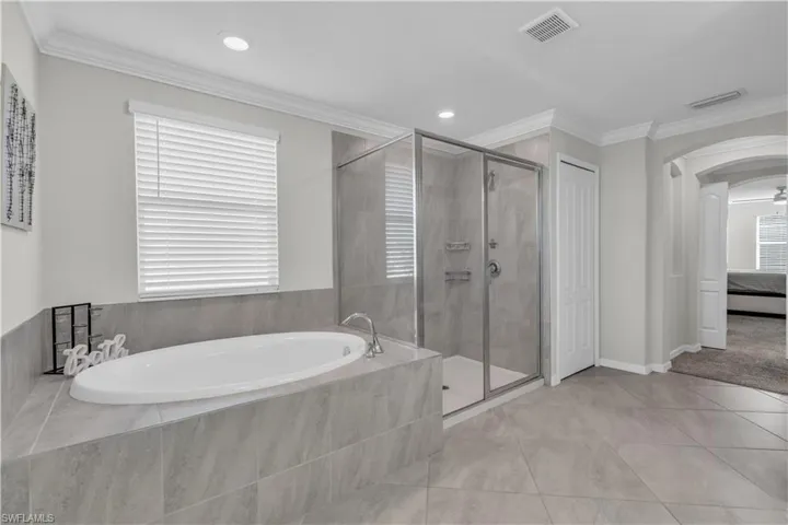 Bathroom featuring separate shower and tub, crown molding, and tile patterned flooring
