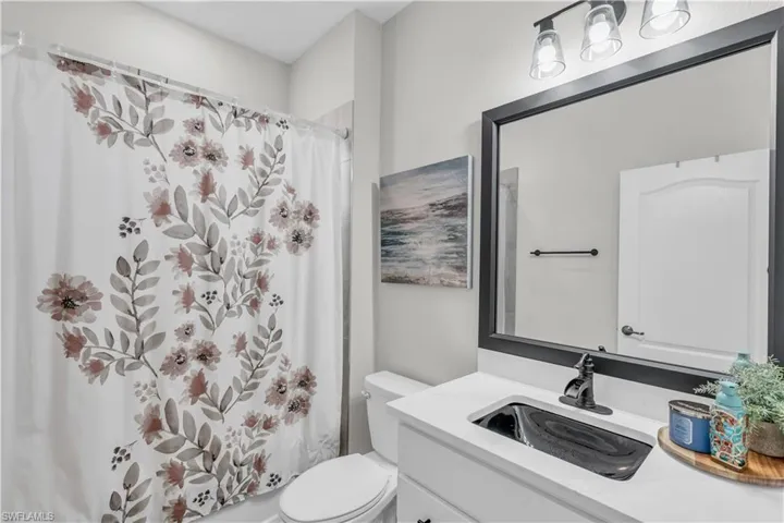 Bathroom featuring curtained shower, vanity, and toilet