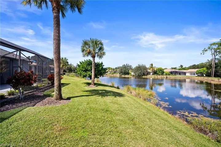 View of green lawn with a water view, glass enclosure, and a sunroom