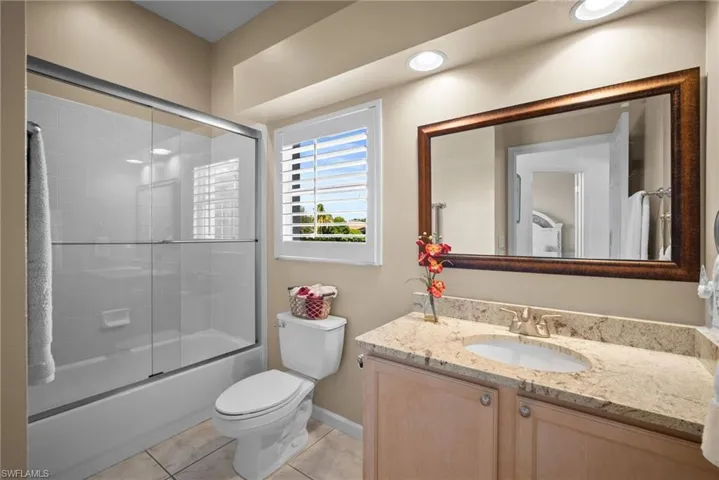 Full bath with vanity, light tile patterned floors, and combined bath / shower with glass door
