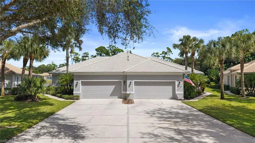 Ranch-style house with a front lawn, a tiled roof, stucco siding, and driveway