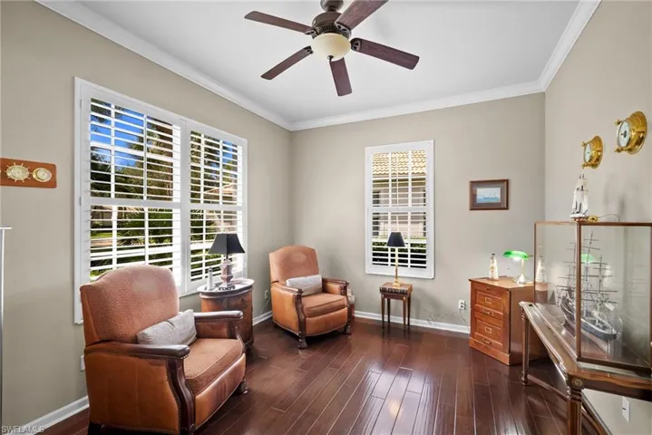 Living area with crown molding, dark wood finished floors, and a ceiling fan