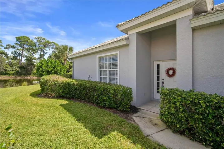 Property entrance featuring stucco siding, a yard, and a water view