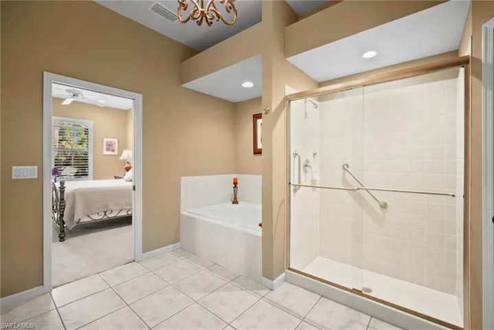 Ensuite bathroom with a stall shower, light tile patterned floors, a bath, and light colored carpet