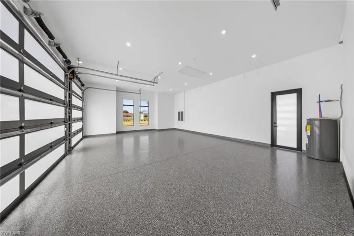 Epoxy-coated 3 car garage with glass paneled garage doors. Side-entry door and curtained windows.