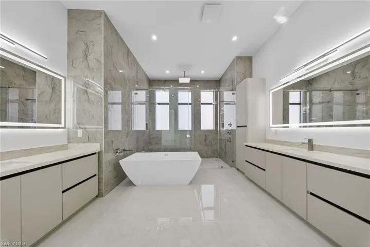 Master bathroom with dual vanities, a freestanding tub, and illuminated mirrors with integrated defogging feautre.