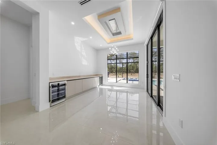 Dining area featuring an extended bar with two built-in wine/beverage coolers. Oversized sliding doors/windows, and recessed lighting.