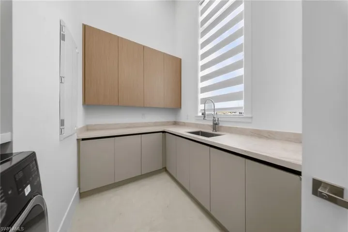Laundry featuring washer / dryer, modern custom cabinets, and a sink.