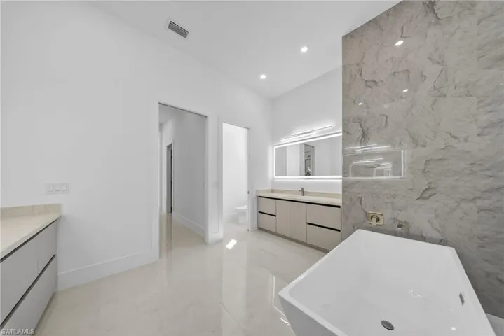 Master bathroom with dual vanities, a freestanding tub, and illuminated mirrors with integrated defogging feautre.