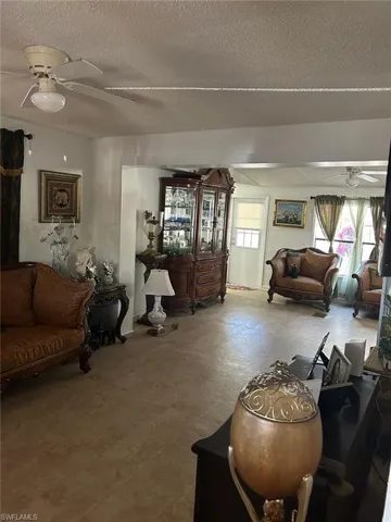 Living area with a ceiling fan, a textured ceiling, and tile patterned floors