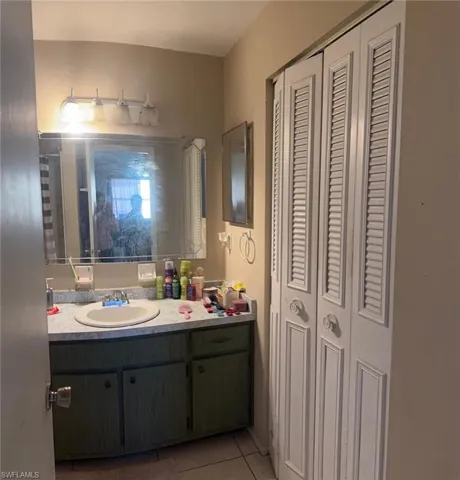 Bathroom with a closet, vanity, and light tile patterned flooring