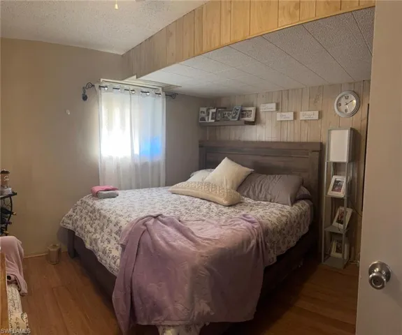 Bedroom featuring wooden walls, wood finished floors, and a textured ceiling