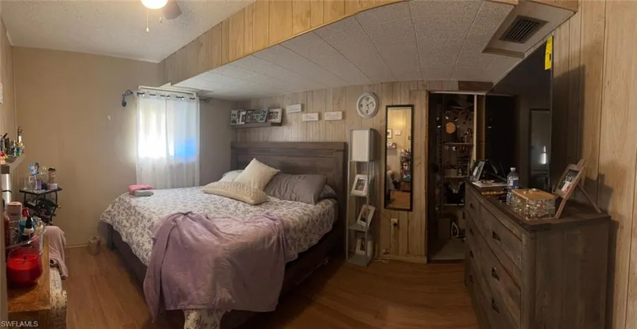 Bedroom featuring wood walls, wood finished floors, and a ceiling fan