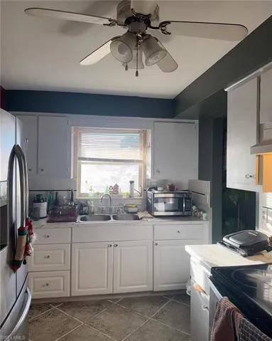 Kitchen featuring stainless steel appliances, white cabinets, light countertops, and a ceiling fan