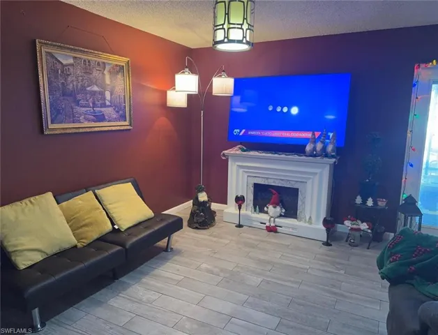Living room featuring wood finished floors, a textured ceiling, and a premium fireplace