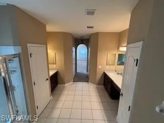 Full bathroom with tile patterned flooring, vanity, visible vents, and a stall shower