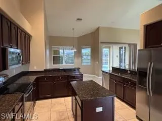 Kitchen with dark stone countertops, a sink, dark brown cabinets, and appliances with stainless steel finishes