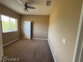 Unfurnished bedroom featuring carpet flooring, baseboards, a ceiling fan, and visible vents