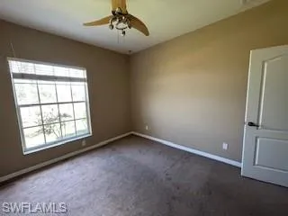 Empty room featuring ceiling fan, carpet flooring, and baseboards