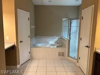 Full bathroom with tile patterned flooring, vanity, a bath, and a stall shower