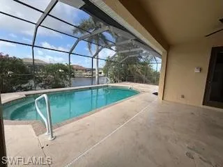 Pool featuring glass enclosure and a patio