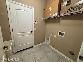 Washroom with baseboards, washer hookup, laundry area, electric dryer hookup, and light tile patterned flooring