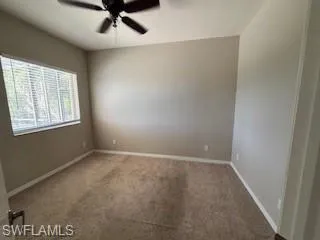 Carpeted spare room featuring baseboards and a ceiling fan
