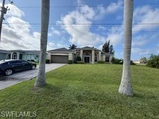View of front facade featuring concrete driveway, a front yard, and an attached garage