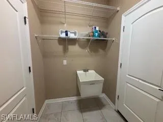 Laundry room featuring light tile patterned floors and baseboards
