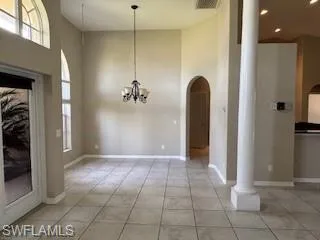 Foyer featuring light tile patterned flooring, decorative columns, a towering ceiling, and visible vents