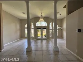 Entryway featuring tile patterned floors, baseboards, lofted ceiling, and ornate columns