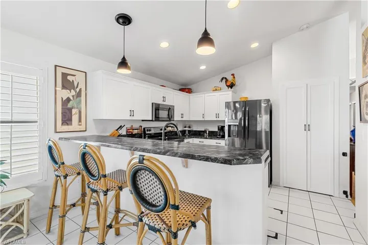 Kitchen featuring white cabinetry, light tile patterned floors, stainless steel appliances