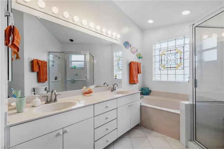 Full bathroom with tile patterned flooring, lofted ceiling, double vanity, toilet, and plus walk in shower