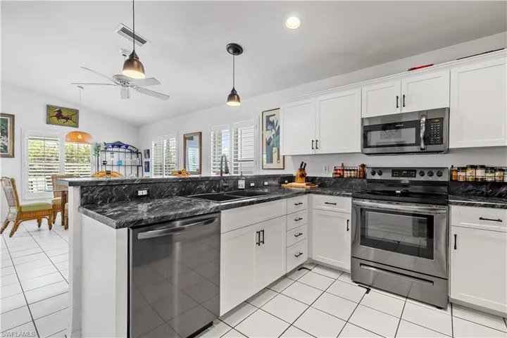 Kitchen featuring hanging light fixtures, a wealth of natural light, light tile patterned floors, and stainless steel appliances
