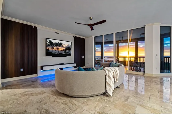 Living area with ornamental molding, light marble finish floors, floor to ceiling windows, and ceiling fan