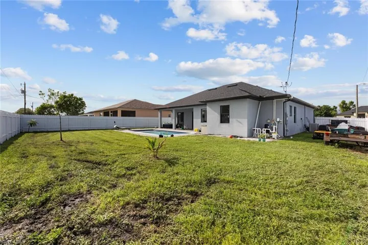 Rear view of property featuring a lawn and a fenced in pool