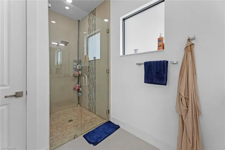 Bathroom with a shower with door and tile flooring