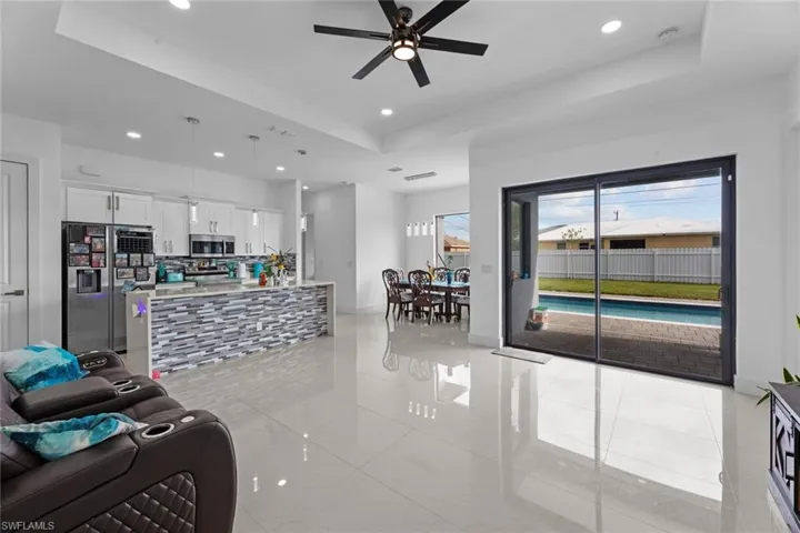 Living room with ceiling fan, light tile flooring, and a raised ceiling