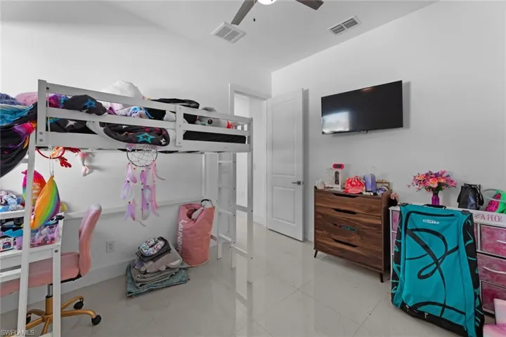 Tiled bedroom featuring ceiling fan