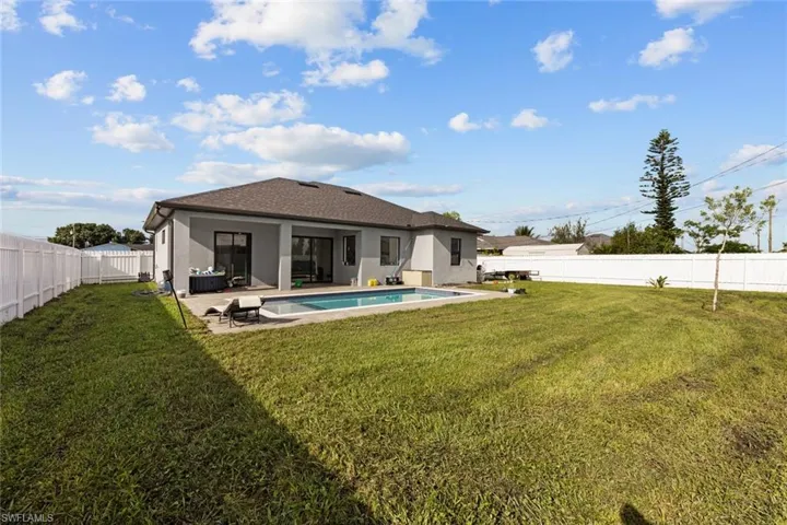 Rear view of property with a patio area, a fenced in pool, and a yard