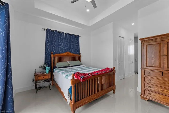 Tiled bedroom featuring ceiling fan and a raised ceiling