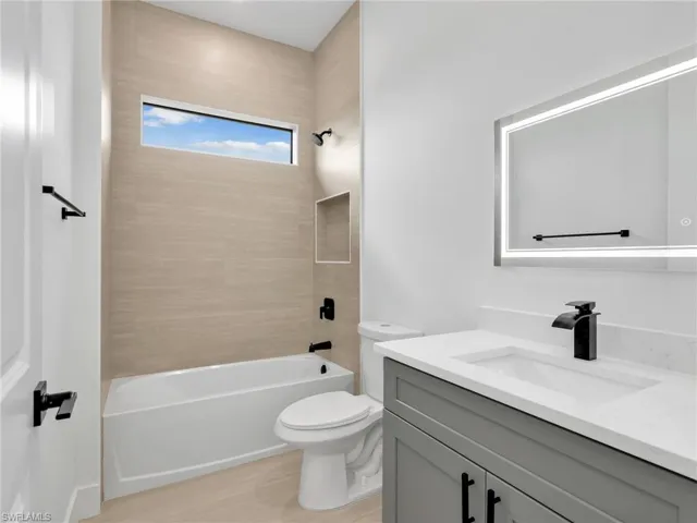 Bathroom featuring vanity,  shower combination, and light wood-type flooring