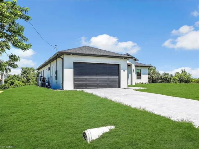 View of front of property with a front lawn, stucco siding, decorative driveway, and a garage