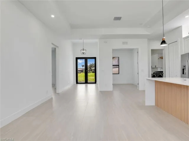 Unfurnished living room featuring recessed lighting, french doors, and a tray ceiling