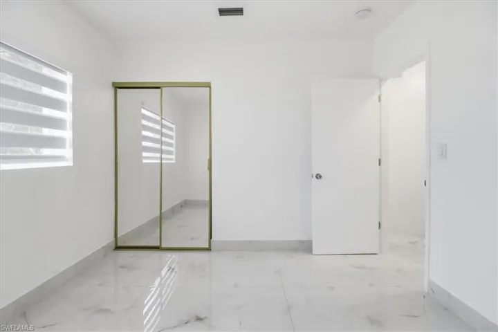 Unfurnished bedroom featuring light marble finish floors and a closet